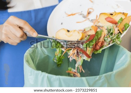 Compost from leftover food asian young housekeeper woman, female hand holding salad bowl use fork scraping waste, rotten vegetable throwing away into garbage, trash or bin. Environmentally responsible Royalty-Free Stock Photo #2373229851
