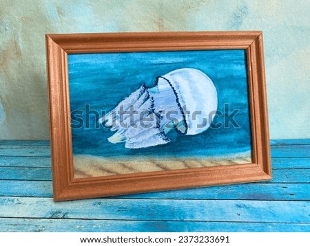 Handmade picture of a jellyfish in wooden frame on blue background