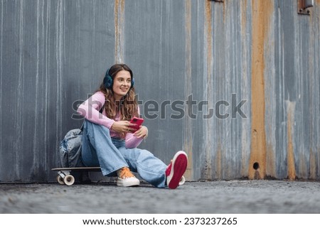 Portrait of generation z girl student sitting outdoors in the city, spending free time online and alone. Concept of gen Z as loneliest generation. Royalty-Free Stock Photo #2373237265