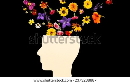 World mental health day concept. Human head symbol and flowers on black background. 