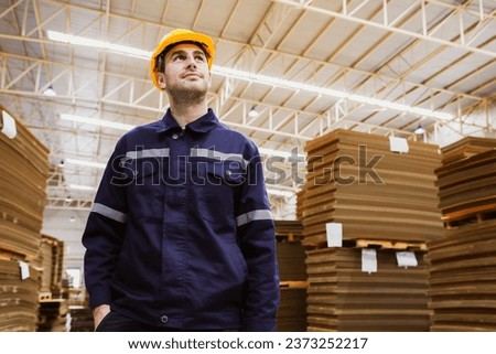 Portrait handsome caucasian man wearing safety helmet professional security guard in cardboard box warehouse export logistics factory standing intelligently patrolling warehouse internal security.