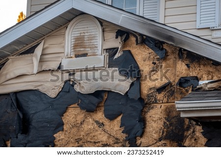 A close-up view of a neighborhood garage roof, which bears the scars of recent accidental fire damage, expertly extinguished by firefighters. Royalty-Free Stock Photo #2373252419