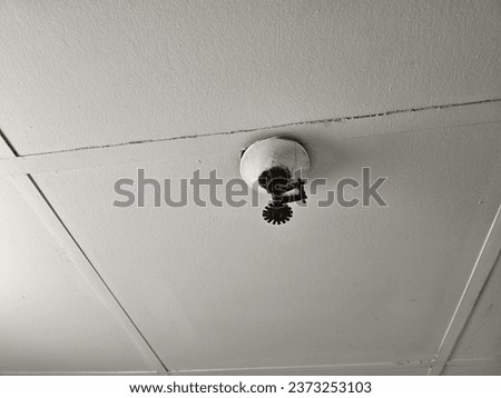 An outdated sprinkler on a ceiling. 