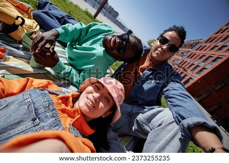 Colorful POV of diverse group of young people taking selfie outdoors while enjoying picnic in city
