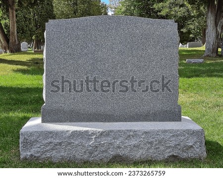 Blank gray granite tombstone in a cemetery Royalty-Free Stock Photo #2373265759