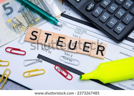 the inscription steuer, i.e. tax, next to banknotes and a calculator. Concept showing taxes in Germany Royalty-Free Stock Photo #2373267485