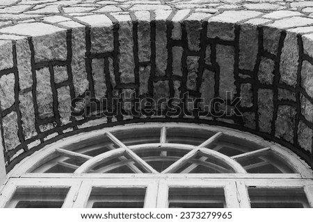 A closeup photo of the arched wooden framed white painted window in black and white viewed f