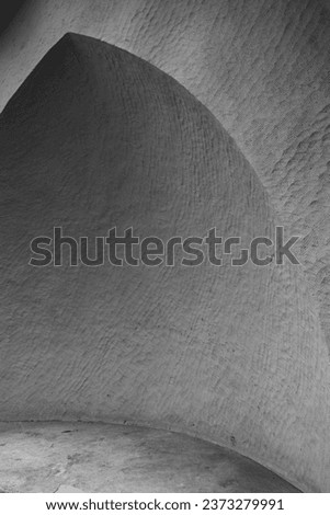 A closeup photo of the triangular alcove in a plastered stone wall forming the linear pattern in black and white.