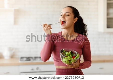 Weight Loss Diet. Happy sporty woman eats a big bowl of fresh salad in the kitchen indoor, slimming, advertising healthy living and nutrition. Easy meal for staying in shape Royalty-Free Stock Photo #2373280913