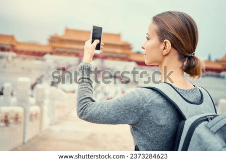 Enjoying vacation in China. Travel and technology. Young woman with smartphone taking photo at Forbidden City, Beijing.