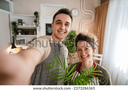 Couple caucasian man and woman wife and husband planting flowers together taking care of home plants real people domestic life family gardening concept take selfie photo with smartphone UGC Royalty-Free Stock Photo #2373286365