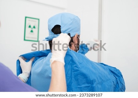 Doctor being helped to put on the sterile gown to perform the surgery. Concept: surgical, operation, sterility Royalty-Free Stock Photo #2373289107