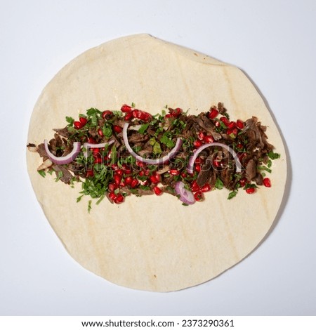 A tortilla filled with a variety of delicious ingredients, including juicy meat "shawarma"  and fresh onions and vegetables 
