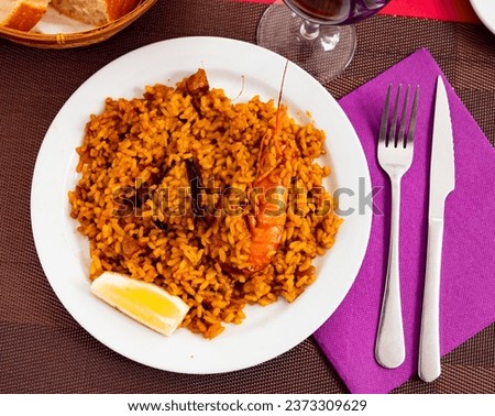 Appetizing racy seafood paella with mussels, calamari rings and prawns served with lemon. Authentic Valencian cuisine.. Royalty-Free Stock Photo #2373309629