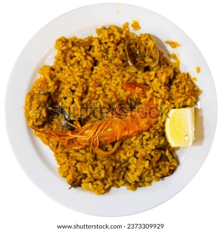 Appetizing racy seafood paella with mussels, calamari rings and prawns served with lemon. Authentic Valencian cuisine. Isolated over white background. Royalty-Free Stock Photo #2373309929