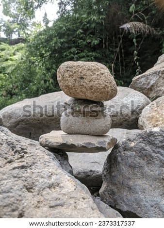 an image of rocks stacked in a waterfall, with a natural background