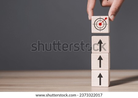 Hand holding wooden block with target icon and arrow aim to target. Business achievement goal and objective target concept.