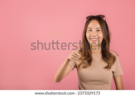 Portrait Asian beautiful young woman smiling she standing made finger thumbs up, Ok sign to agree studio shot isolated on pink background, Thai female successful like finger gesture with copy space
