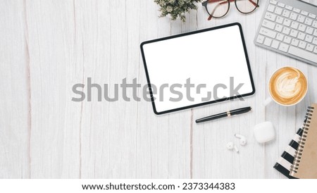 White wooden desk workplace with blank screen tablet, keyboard, pen, eyeglass, notebook and cup of coffee, Top view flat lay with copy space.
