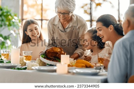 Thanksgiving Day, Autumn feast. Happy family sitting at the table and celebrating holiday. Grandparents, mother and children. Traditional dinner.