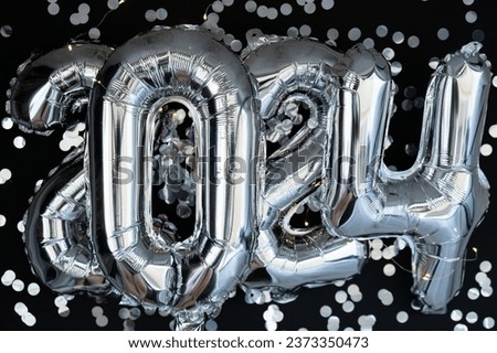 Happy new year 2024 metallic balloons with confetti on dark black background. Greeting card silver foil balloons numbers Christmas holiday concept. Celebration party congratulation