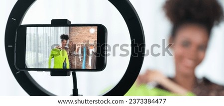 Woman influencer shoot live streaming vlog video review clothes crucial social media or blog. Happy young girl with apparel studio lighting for marketing recording session broadcasting online. Royalty-Free Stock Photo #2373384477