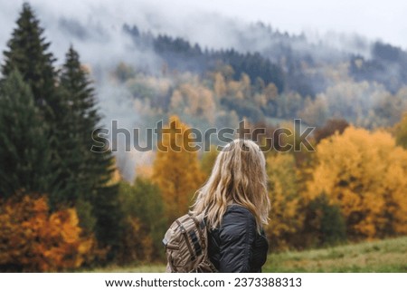 Hiking in autumn forest. Woman during hike in mountain. Fog weather Royalty-Free Stock Photo #2373388313