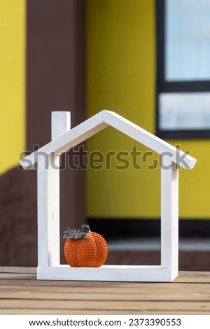 Autumn decor on porch of yellow house outside of pumpkin, lantern, garlands and figure of home and key. Halloween party, autumn mood, Harvest festival, real estate, insurance, mortgage