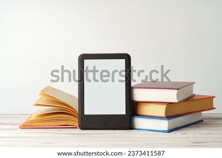 Digital tablet with a stack of books on gray background