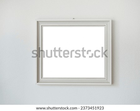 A realistic image of a white wooden picture frame filled with white canvas hanging on a white wall.