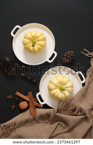 Autumn Thanksgiving background with pumpkins on ceramic pans and brown cloth on black background. Top view. Advertising photo for the Thanksgiving holiday.