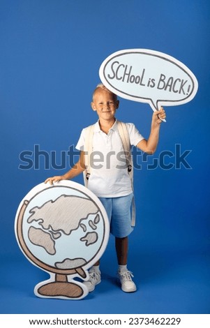 Schoolboy with big cartoon globe and an inscription school is back in his hand and a backpack.