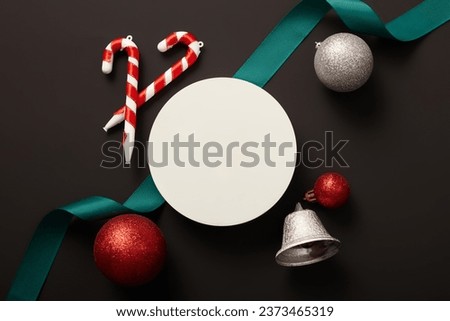 Flat lay of a round podium displayed with sparkling baubles, candy cane and a ribbon. Christmas traditions include a variety of customs, religious practices and rituals