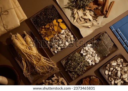 View from above of a lot of herbal medicine are displayed with few packs of medicine and two ancient Chinese medicine books. Precious medicine for health Royalty-Free Stock Photo #2373465831