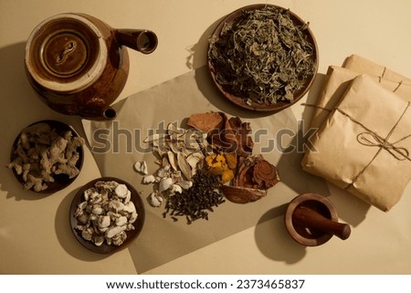 Bai zhu, Sand ginger, Cloves and Dried turmeric slices are placed on a paper. An earthen pot and some packs of traditional medicine displayed. Natural medicine content Royalty-Free Stock Photo #2373465837