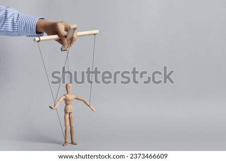 Woman pulling strings of puppet on light grey background, closeup. Space for text Royalty-Free Stock Photo #2373466609
