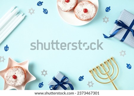 Jewish holiday Hanukkah concept. Flat lay frame of jelly donuts, menorah, candles, gift boxes on pastel blue background.