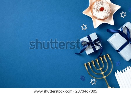 Jewish holiday Hanukkah concept. Flat lay composition with traditional jelly donut, menorah, candles and gift boxes on blue background. Flat lay, top view.