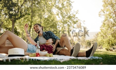 Smiling couple taking selfie on picnic. Woman lying on boyfriend's lap and taking selfie with her mobile phone.