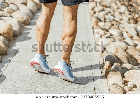 Shows the muscles on the legs of a sporty man runner. Getting ready to start jogging in running shoes.