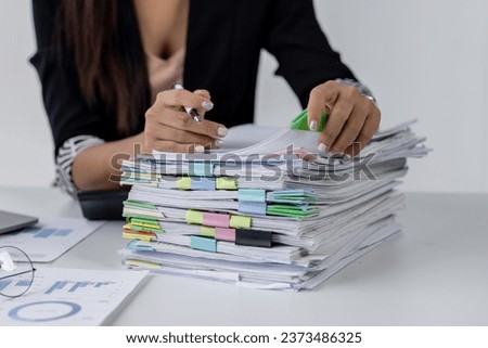Businesswoman hands working in Stacks of paper files for searching and checking unfinished document achieves on folders papers at busy work desk office
