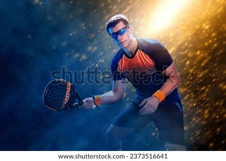 Padel tennis player. Padel open tour. Man athlete with paddle tenis racket and ball on fire background. Sport concept. Download a high quality photo for sports ads at social media stories or shorts.