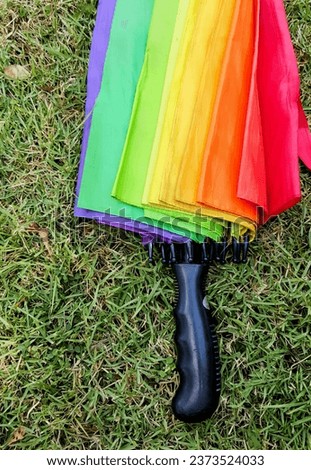 a rainbow colored umbrella lying on the grass.