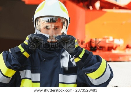 Firefighter portrait on duty. Photo fireman with gas mask and helmet near fire engine