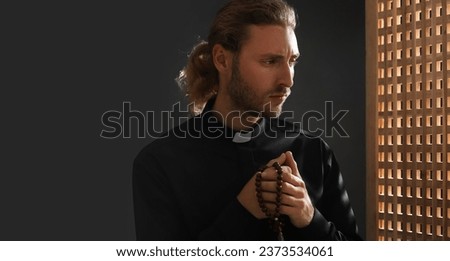 Portrait of male priest in confession booth