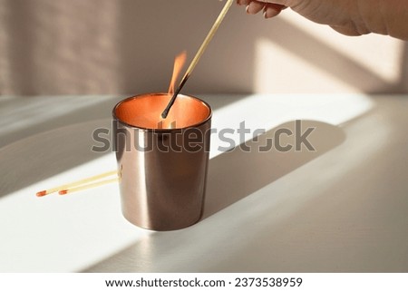 A woman lights an aromatherapy candle with a match.