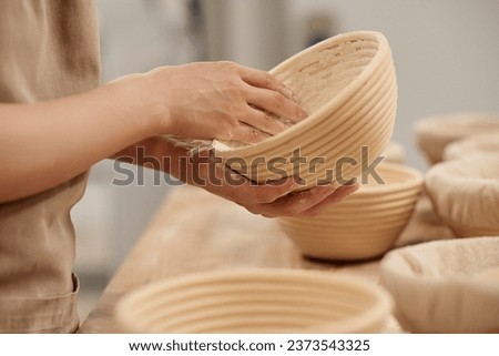 Close up of unrecognizable young woman powdering bowls for fresh dough while working in bakery kitchen, copy space