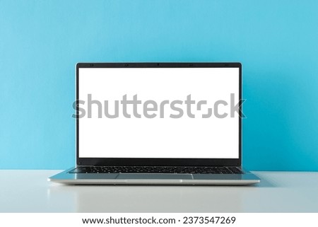 Freelance work in focus. Side view photo of contemporary laptop graces a minimalist tabletop against a blue wall backdrop, offering space for your text or advertizing Royalty-Free Stock Photo #2373547269