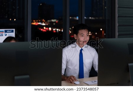 Portrait of young Asian businessman working in office at night. Business and technology concept.