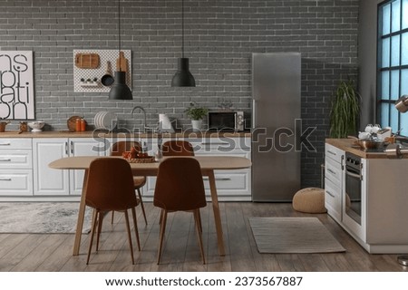 Interior of modern kitchen with white counters, dining table and fridge